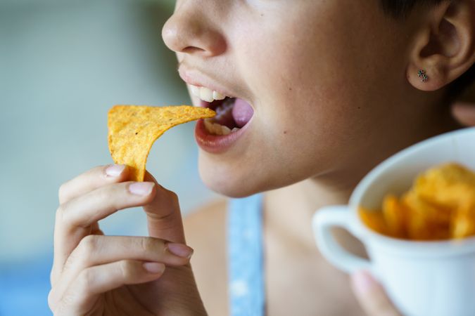 Anonymous girl about to eat yummy nacho chip at home
