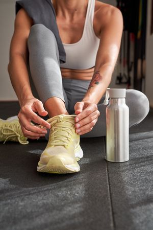 Crop sportswoman tying laces on sneakers
