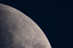 Detailed lunar surface view highlighting illuminated craters and plains.