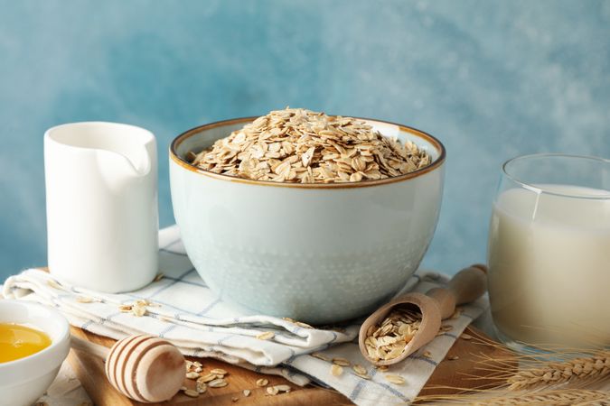 Composition with oatmeal flakes and milk on table. Cooking breakfast