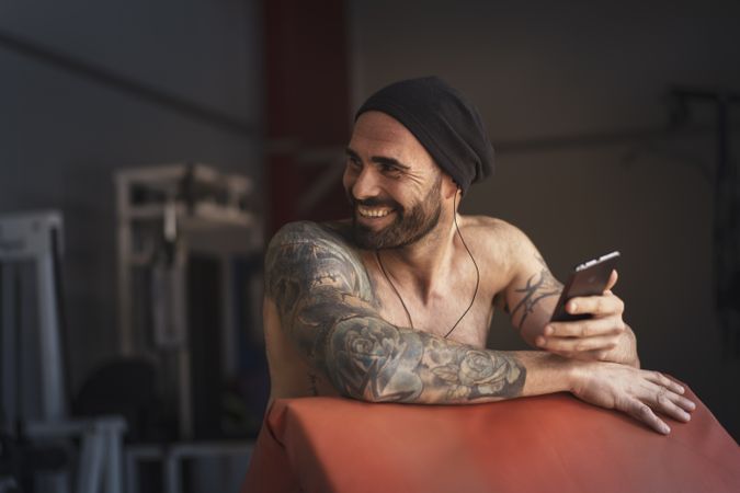 Laughing athlete with smartphone in gym