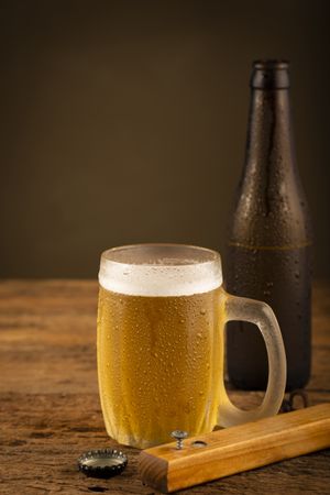 Glass full of cold beer on the wooden table