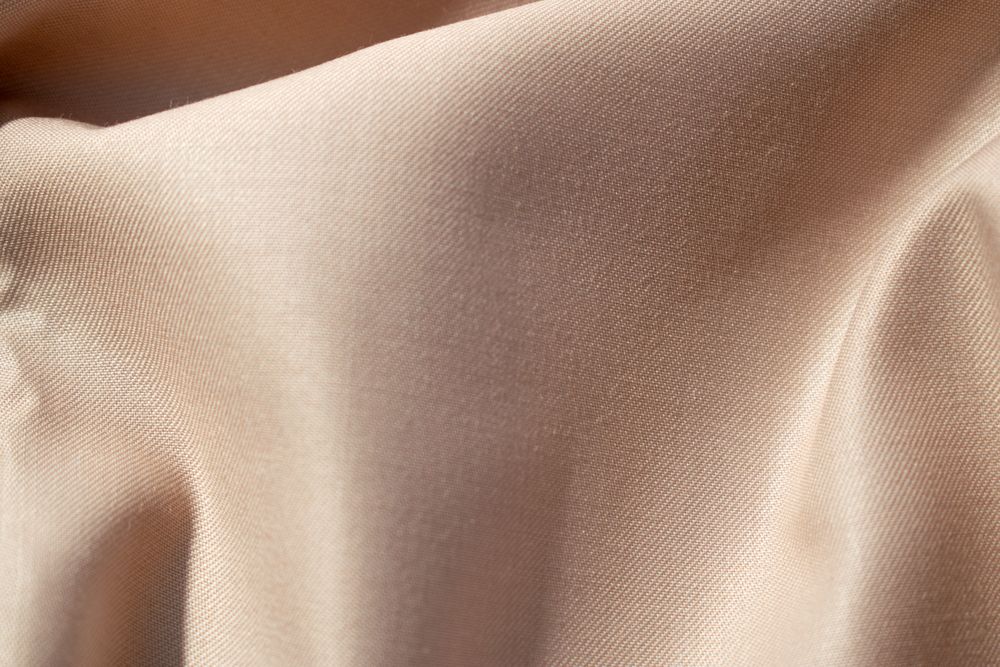 Close up silk shiny light brown fabric background texture.