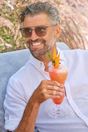Cheerful man with cocktail sitting on bench