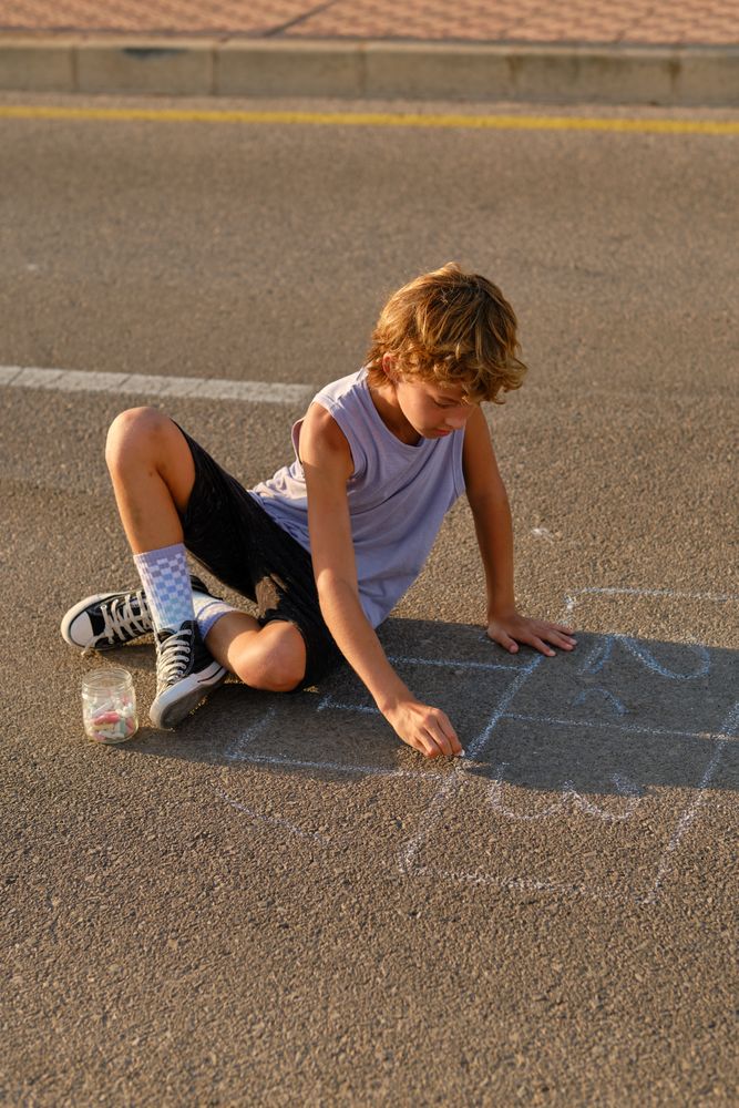 Child drawing with chalk on asphalt