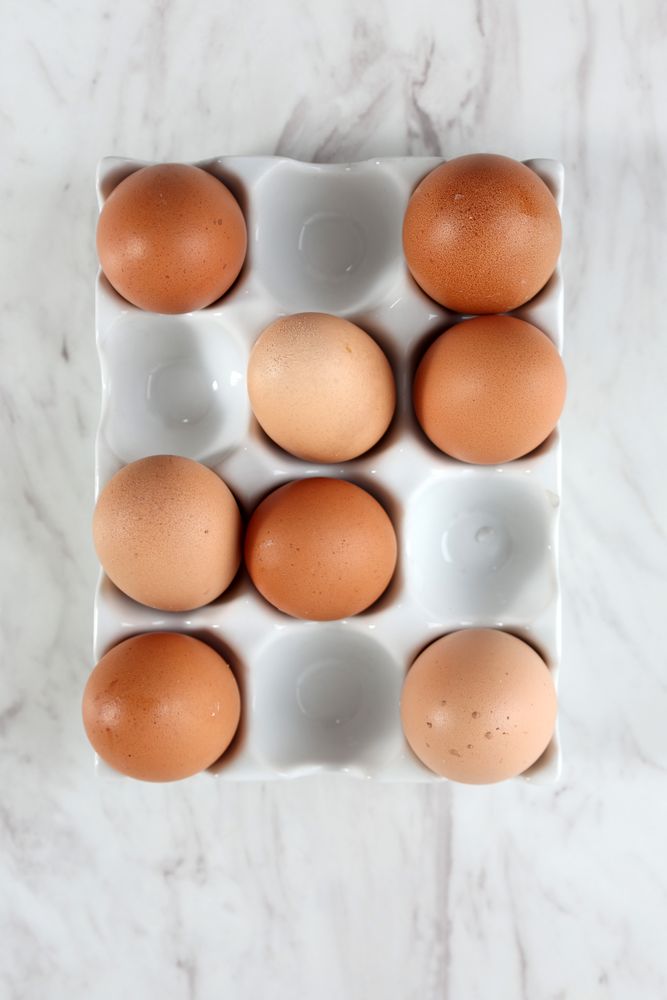 Eggs on Ceramic Egg Tray, Isolated on Marble Table