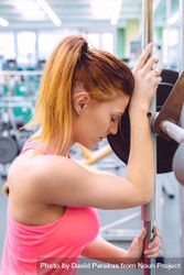 Red haired woman leaning on barbell in between lifting 5rpo7b