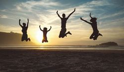 Silhouettes of children jumping in the beach at sunset