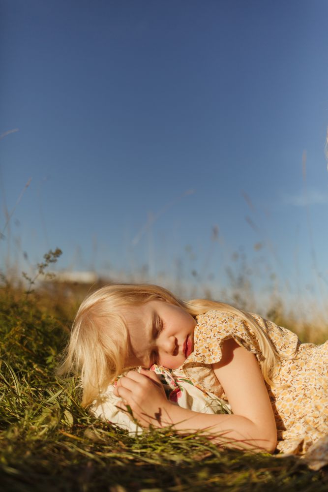 Calm little girl lying in countryside field
