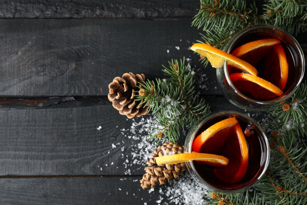 Glasses of tasty mulled with orange on decorated background, space for text