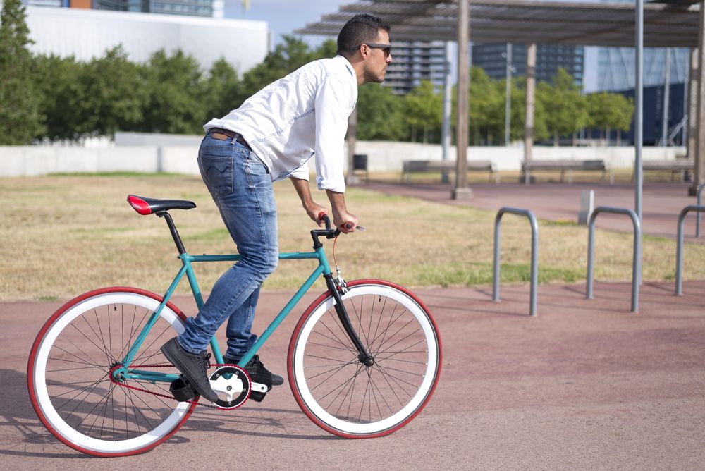 Male riding red and green bike outside on nice day