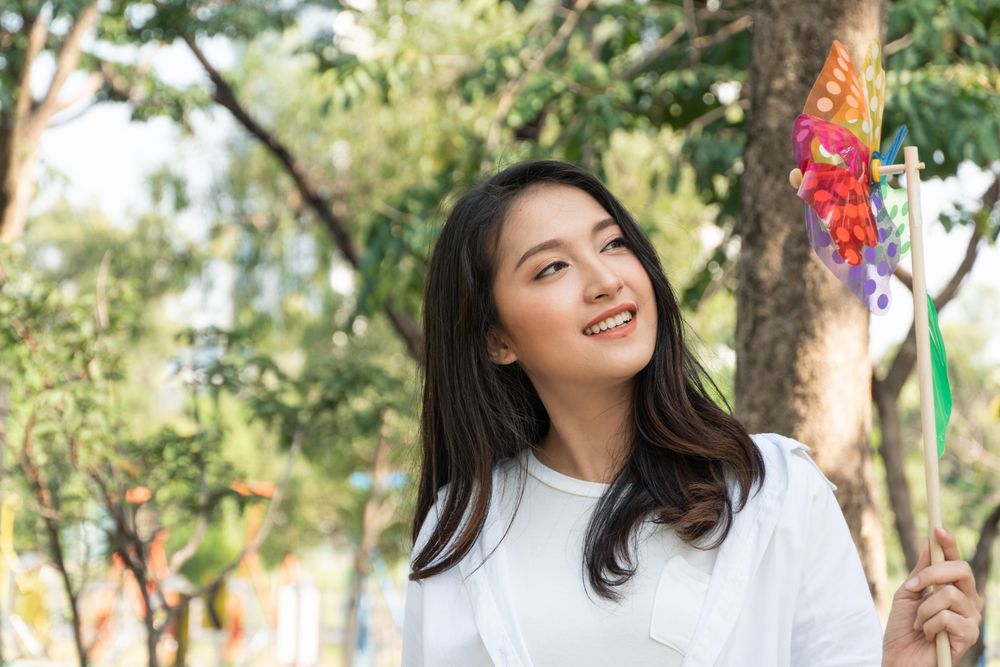 Woman smiling at colorful wind toy in park