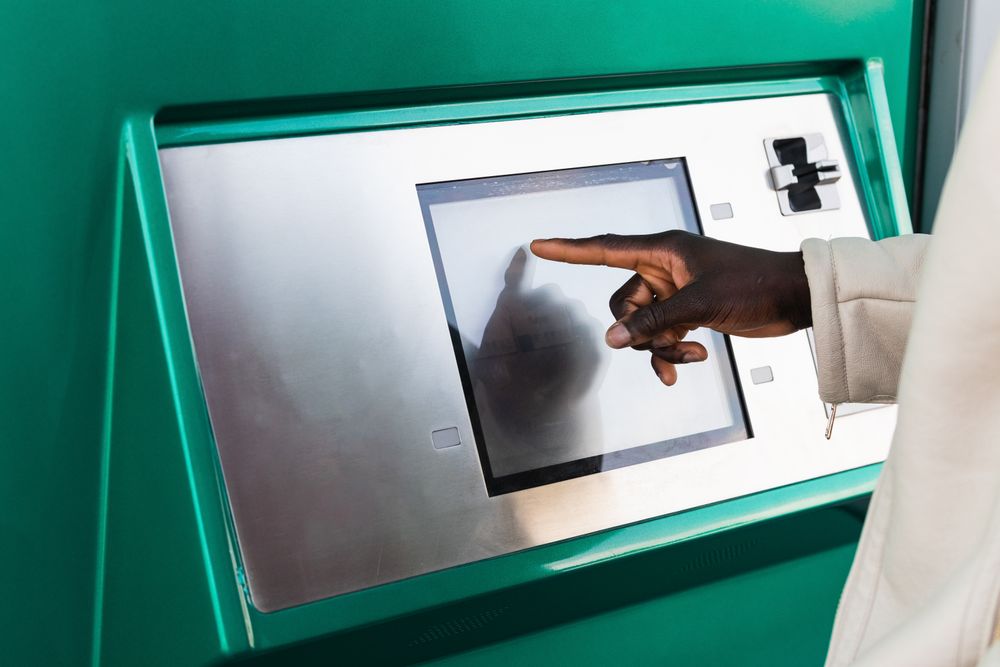 Anonymous Black businessman touching screen of ATM in town