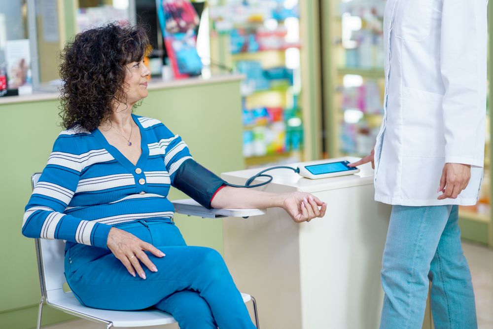 Mature woman having blood pressure taken in pharmacy