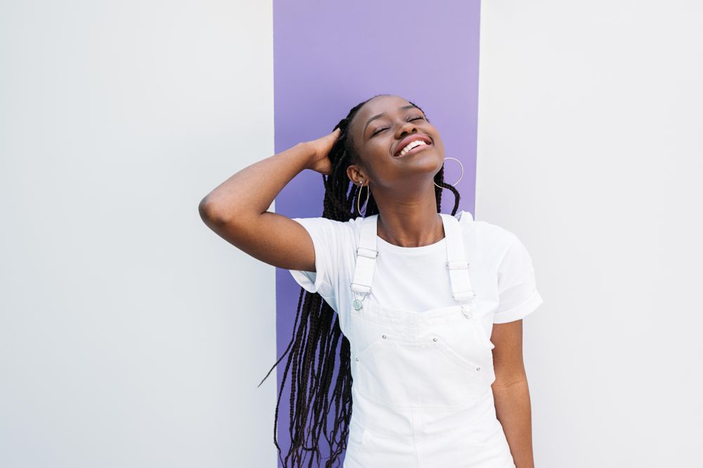 Black woman with long braids smiling with her head back