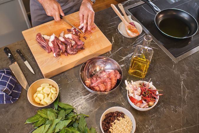 Unrecognizable person cutting octopus on kitchen table