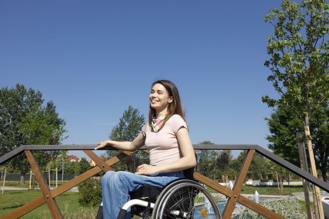 Happy woman in a wheelchair on a bridge