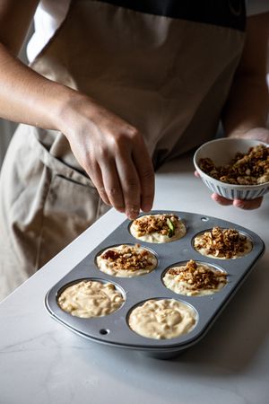 Faceless person cooking muffins with walnuts