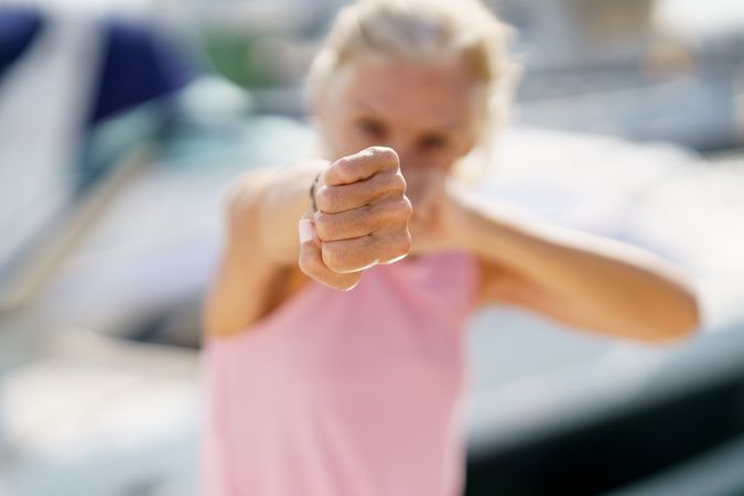 Fist of mature woman practicing boxing on a coastal pier