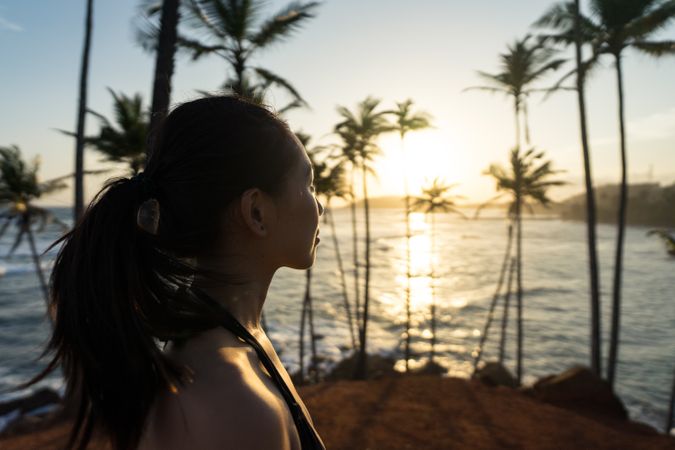 Tranquil female traveler among palms at seashore