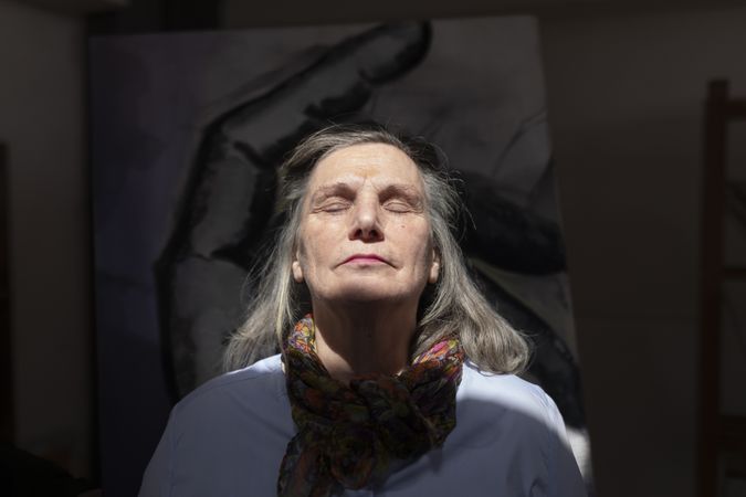 Mature artist woman enjoys the light that enters through a skylight