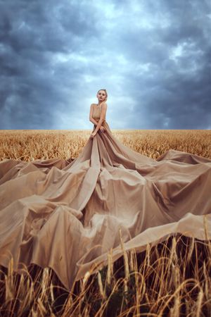 Woman in big brown dress in wheat field during daytime