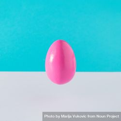 Pink egg suspended on blue background bxD6jb