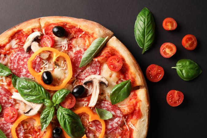 Delicious pizza and tomatoes on dark background, close up