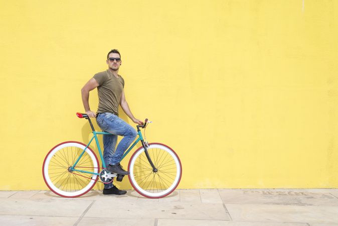 Male sitting on bike in front of yellow wall