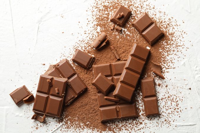 Tasty chocolate and powder on blank background. Sweet food
