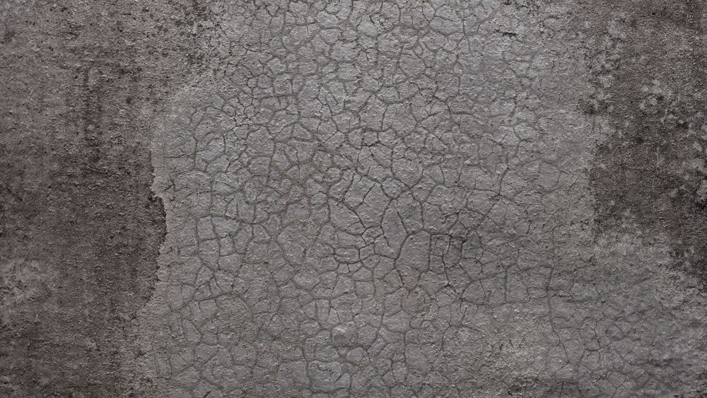 Cracked gray concrete wall with rough texture and aged surface details