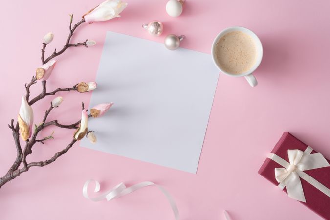 Flowers on brown branch on pastel pink background with paper card