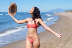 A joyful woman enjoys the beach, soaking up the sun in her bright, colorful summer attire