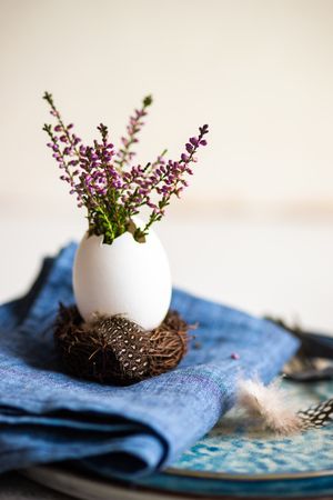 Side view of Easter table setting with egg shell and heather on blue plates