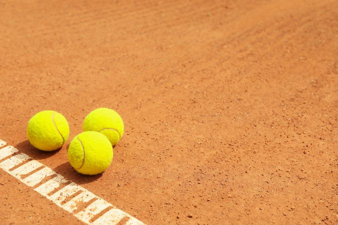 Light green tennis balls on clay court
