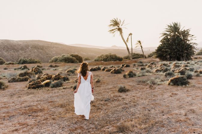 Woman in white dress in dry field in sunlight