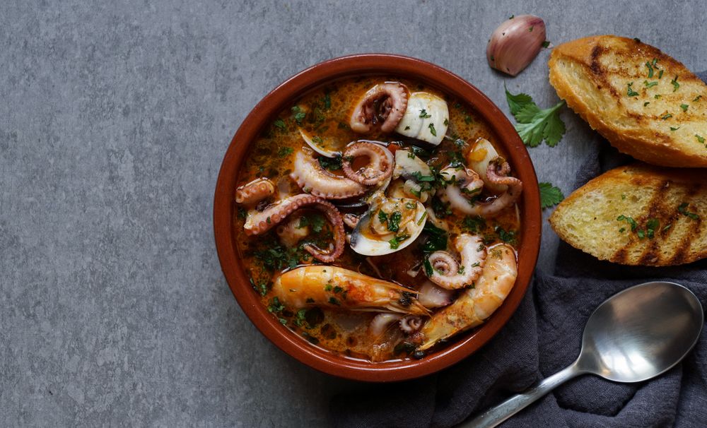Soup of octopus and shrimps near toasts and spoon