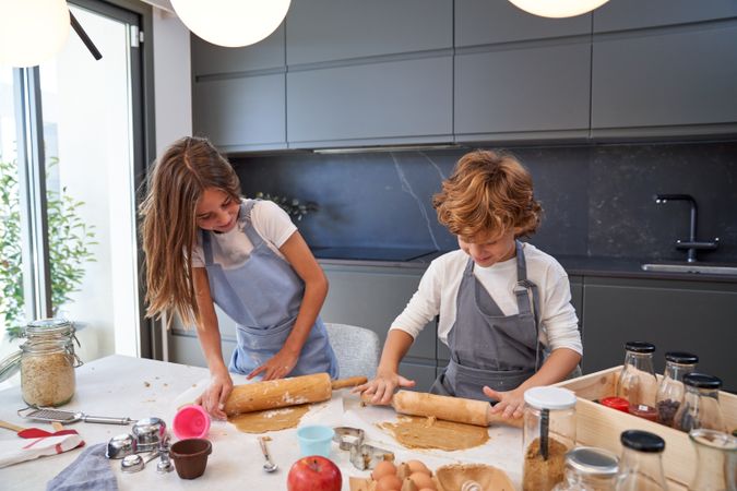 Smiling kids making dough during pastry preparation in kitchen