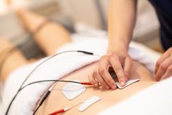Physiotherapist adjusting electro pads on lower back of woman
