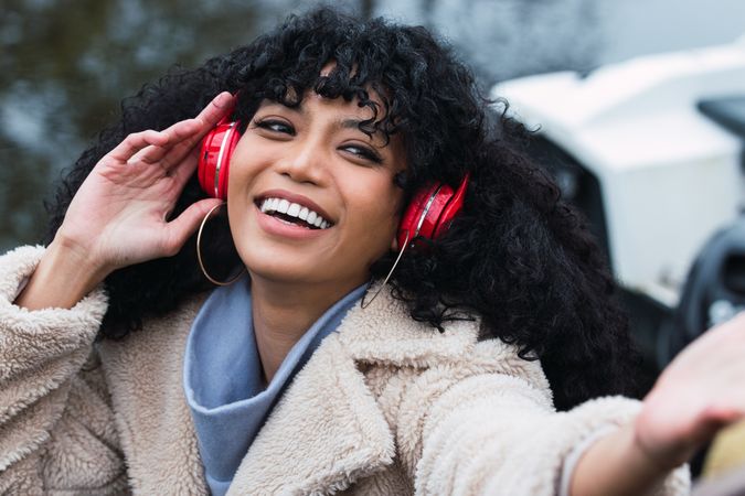 Cheerful Black woman listening to music in headphones