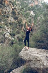 Happy woman standing on boulder in valley