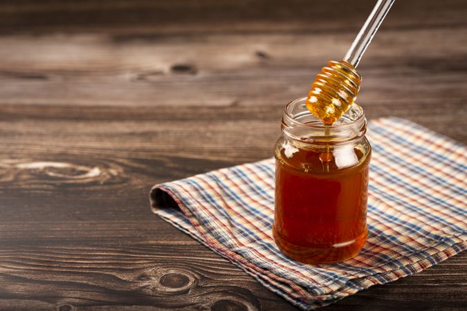 Honey in glass jar on the table.