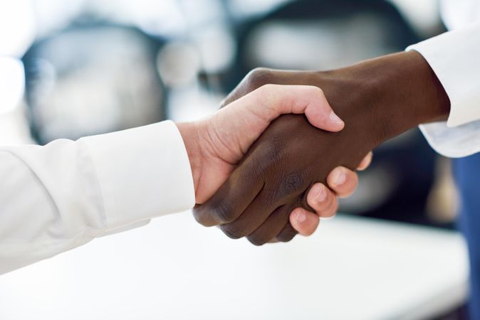 Close up of a Black and white male shaking hands in professional setting
