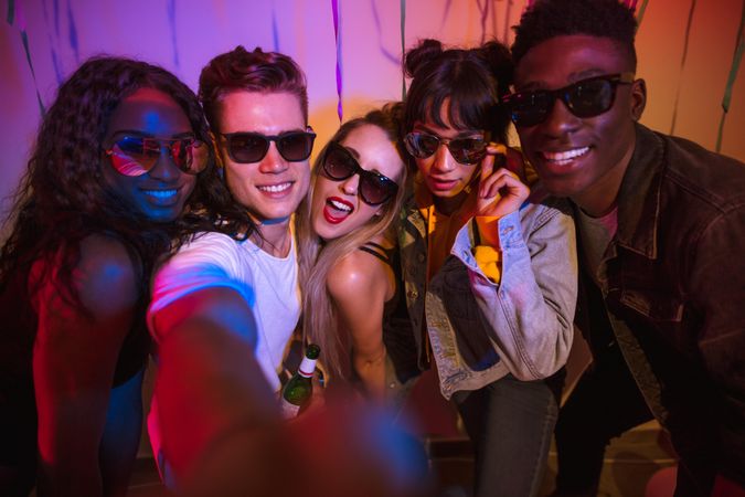 Young men and women posing and having fun at a colorful house party