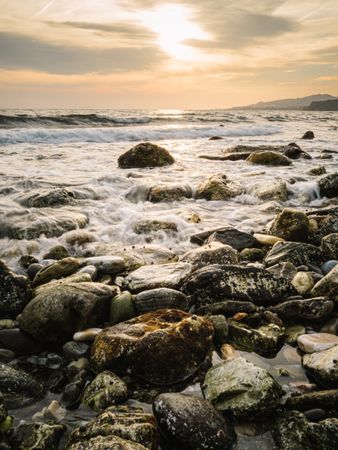 Stony seashore and waves at beautiful sunset