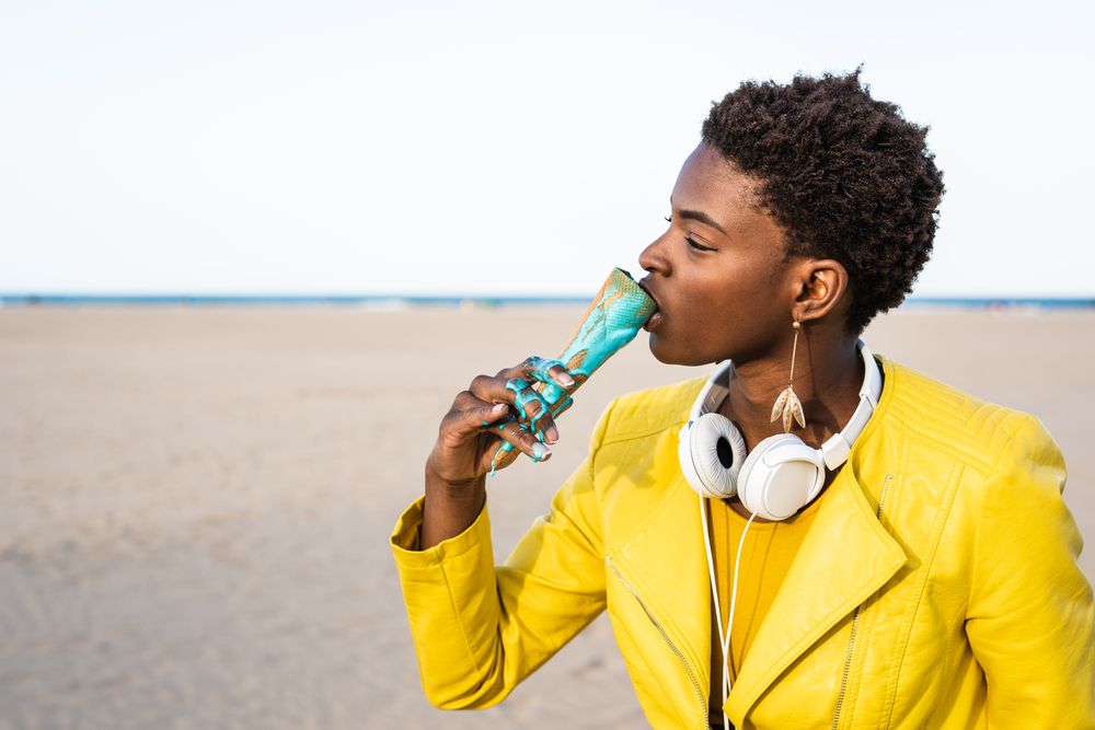 Cool female eating ice cream on beach