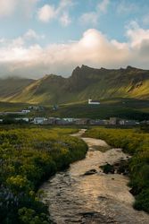 Wooden houses in green mountain valley under cloudy sky