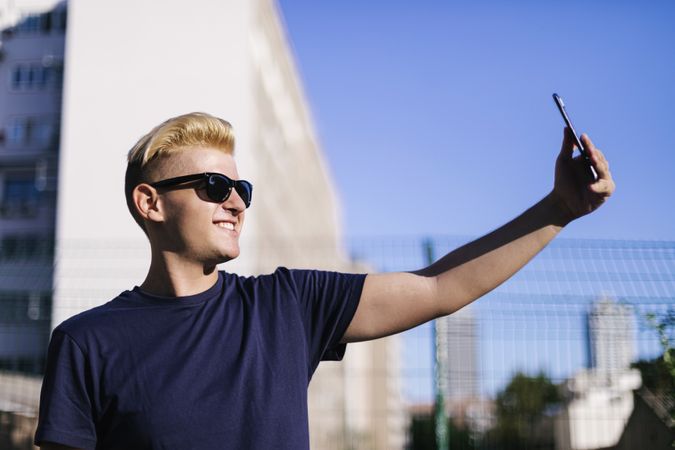 Man with sunglasses taking a selfie outdoors