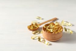 Omega pills in a wooden bowl on a neutral background