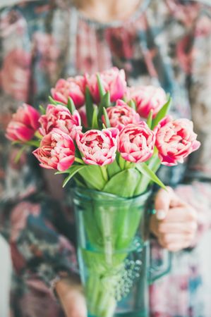 Florist holding new floral arrangement of pink tulips